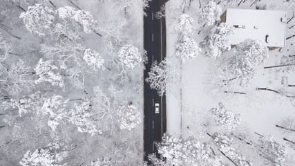 Aerial view of snow covered road in winter forest, truck passing by, motion blur