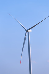 One single windmill turbine with blue sky in background. Renewable energy wind turbine