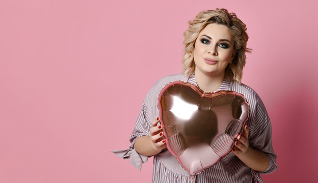 Woman hold heart balloon smiling on pink background. Love valentines day