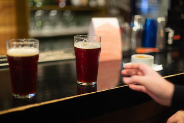 Beer glasses with dark beer are on the bar counter