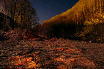 Fototapeta premium Night picturesque view. The wonderful starry sky s time and the majestic mountain range, with glowing villages below. Some digital noise due to high iso.
