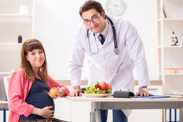 Pregnant woman visiting doctor discussing healthy diet