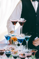 Barman near the pyramid of cocktails