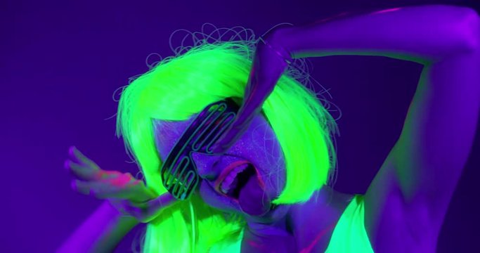 Slow motin of beautiful sexy women with fluorescent make-up and clothing dancing in neon light. Night club, Party Concept.
