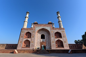 Obraz premium The famous Akbar Tomb in Agra has three-story minarets at each corner and is built of red sandstone strikingly inlaid with white-marble geometric patterns in Agra,India