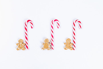Christmas layout. Striped red-white cane candies and homemade ginger cookies on a white background. New Year 2019, christmas, winter concept. Copy space, tov view, flat lay composition.