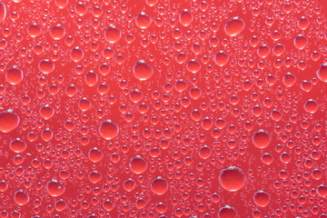 Red water drops or droplets on a glass close up macro shot. Rainy days. 