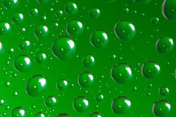 Green water droplets on a glass close up macro shot. Rainy days. 