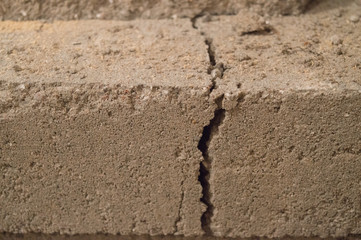 Fototapeta na wymiar A crack through the middle of a dusty concrete block.