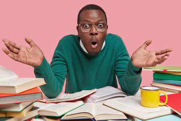 People, exam preparation and studying concept. Puzzled dark skinned wonk demonstrates hesitation...