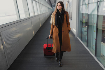 Businesswoman on airport talking on the smartphone while walking with hand luggage in train station or airpot going to boarding gate. Girl using mobile phone for conversation.