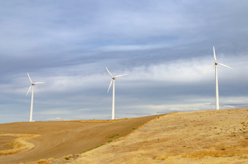 Wind turbines in Oregon countryside with dramatic sky. Wind farm in fields, example of alternative energy resource in use. 