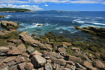 The rugged coast of Acadia National Park, Maine, under wispy clouds on a sunny summer day.