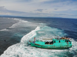 Green tucker boat stranded or has run aground near the beach with waves passing underneath and...