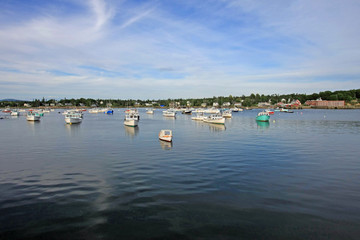 Fototapeta na wymiar Lobster boats of Bass Harbor, Maine, at anchor in the harbor on a quiet summer afternoon.