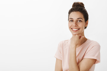 Charming ambitious and charismatic young female smiling roadly holding hand on chin and gazing...