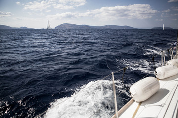 Fototapeta na wymiar Beautiful dark sea in Greece and the part of white boat. Mountains and boats on the background