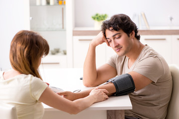 Fototapeta premium Wife checking husband's blood pressure 