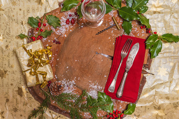 Christmas holiday place setting for dinner: vintage cutlery on red napkin, gift box, wineglass,...