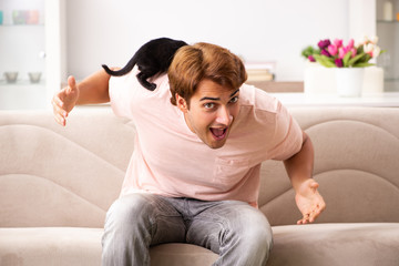 Young man playing with kitten at home