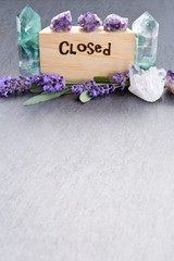 Closed Sign - word burnt in wood with purple lavender flowers, amethyst, fluorite and quartz crystals on slate background