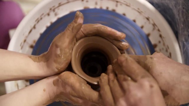 Close-up hands of a male potter in apron molds bowl from clay. Hobby,lifestyle concept.