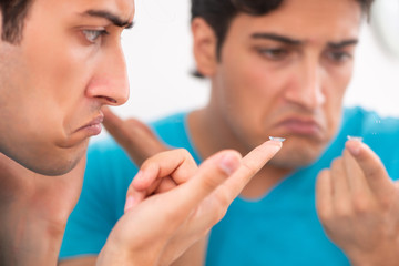 Man trying contact lenses at home