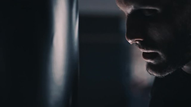 young fit boxer excercising and punching a boxing bag