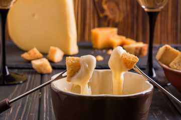 Close up. Gourmet Swiss fondue dinner on a winter evening with assorted cheeses on a board...