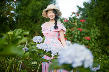 Beautiful girl with a field of hydrangea flowers.