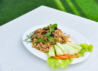 spicy minced pork salad on white plate / cook minced pork mash spicy with herb and fresh vegetable