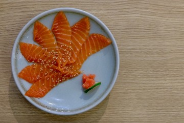 Salmon sashimi with white plate on wood background