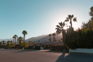 The sun goes behind the mountains before the dusk in Palm Springs, California, USA. A stream of sunlight on the mountains surrounding Palm Springs town boulevard before sunset.