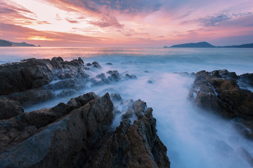 Fototapeta na wymiar Long exposure image of Dramatic sky and wave seascape with rock in sunset scenery background.