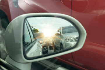 Side view of car mirror traffic of rear-end vehicles on the road with sunlight.