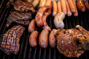 Closeup of mixed grilled sausages and barbecue steak on the grill