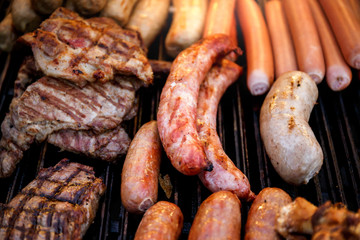 Closeup of mixed grilled sausages and barbecue steak on the grill