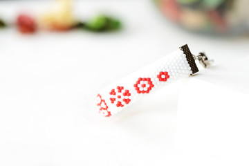 Fototapeta na wymiar White beaded bracelet with red flower print close up