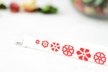 White beaded bracelet with red flower print close up
