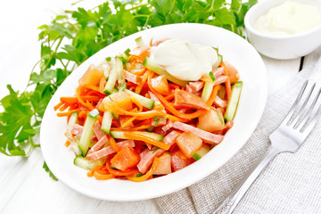 Salad of sausage and spicy carrots on light wooden board