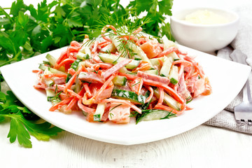 Salad of sausage and spicy carrots with mayonnaise on light wooden table