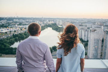 loving couple standing on the roof and watching on the city