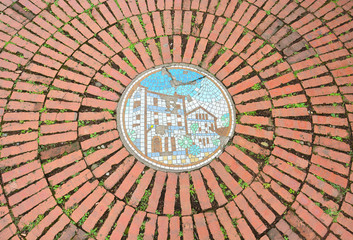 Fototapeta na wymiar red brick pavement in public park, a circular of old red brick floor pattern background texture with mosaic picture in the middle, Taipei, Taiwan
