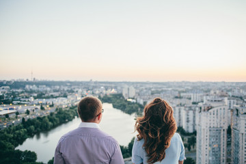 loving couple standing on the roof and watching on the city