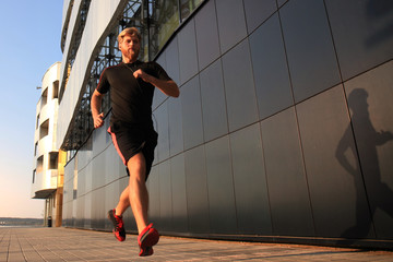 Sporty young man running outdoors to stay healthy, at sunset or sunrise. Runner.