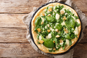 Italian cuisine thin pizza with fresh spinach, garlic and cheese close-up on a board. horizontal top view - Powered by Adobe