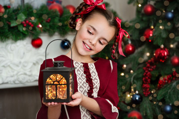Beautiful girl with lantern in retro dress near classic christmas tree at home. Series.
