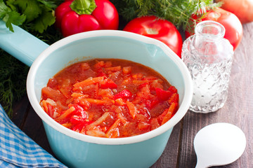 Letcho with tomatoes, peppers and carrots in an enamelled ladle, horizontal