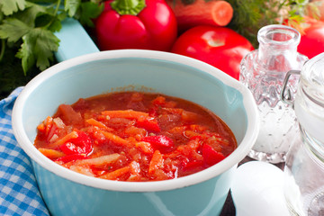 Letcho with tomatoes, peppers and carrots in an enamelled ladle, horizontal