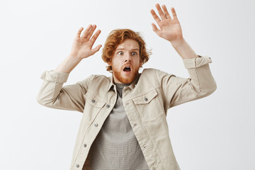 Panicking frightened insecure redhead guy gasping with opened mouth looking right worried and...